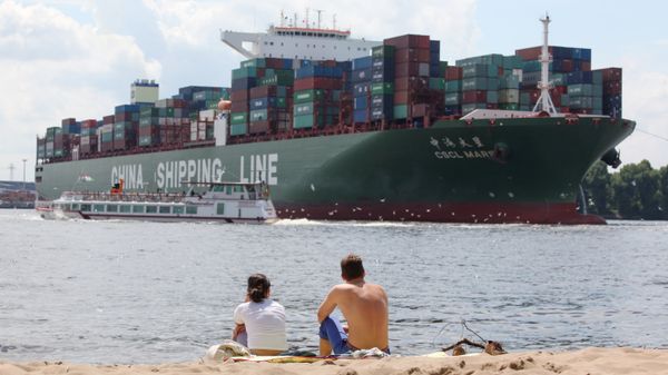 Two people sit on the beach and watch the CSCL Mars container ship of the China Shipping company (File) - Sputnik International
