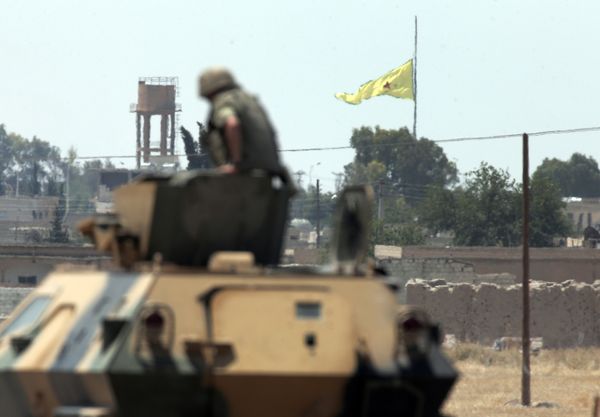 In this photo taken from the Turkish side of the border between Turkey and Syria, in Akcakale, southeastern Turkey, a Turkish soldier on an armoured personnel carrier watches as in the background a flag of the Kurdish People's Protection Units, or YPG, is raised over the city of Tal Abyad, Syria, Tuesday, June 16, 2015 In this photo taken from the Turkish side of the border between Turkey and Syria, in Akcakale, southeastern Turkey, a Turkish soldier on an armoured personnel carrier watches as in the background a flag of the Kurdish People's Protection Units, or YPG, is raised over the city of Tal Abyad, Syria, Tuesday, June 16, 2015 - Sputnik International