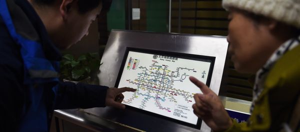 An attendant (L) explains details of new charges to a commuter in front of a subway map at a subway station in Beijing on December 29, 2014 - Sputnik International