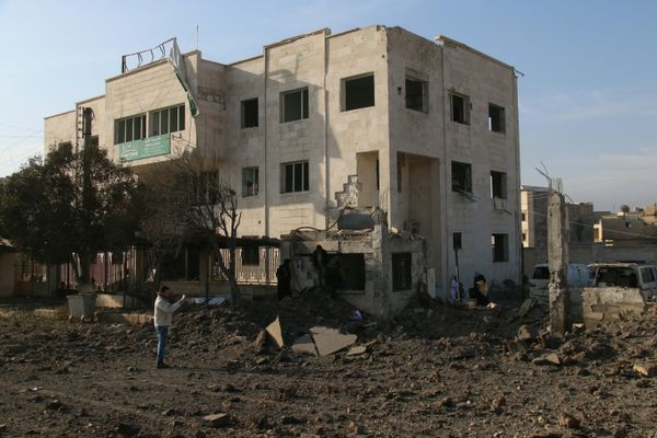 Syrians stand outside a damaged charity clinic for women and children following reported air strikes in the city of Azaz, on Syria's northern border with Turkey, on February 15, 2016. - Sputnik International