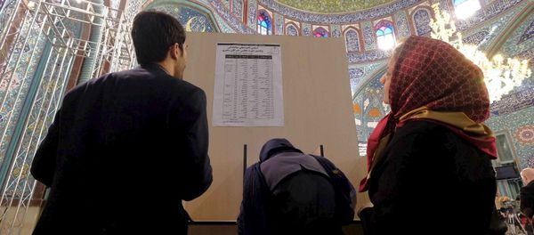 Iranians look at a list of candidates' names during elections for the parliament and Assembly of Experts, which has the power to appoint and dismiss the supreme leader, at a polling station in Tehran February 26, 2016 - Sputnik International
