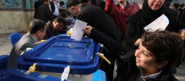 An Iranian boy casts his father ballot for both parliamentary elections and the Assembly of Experts at a polling station in Tehran on February 26, 2016 - Sputnik International