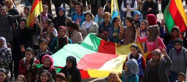 Kurdish people carry flags as they march during a protest in the city of al-Derbasiyah, on the Syrian-Turkish border, against what the protesters said were the operations launched in Turkey by government security forces against the Kurds, February 9, 2016 - Sputnik International