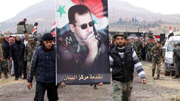 Syrian volunteers and their relatives wave the national flag and portraits of President Bashar al-Assad as they celebrate at the end of a paramilitary training conducted by the Syrian army in al-Qtaifeh, 50 kms north of the capital Damascus on February 22, 2016 - Sputnik International