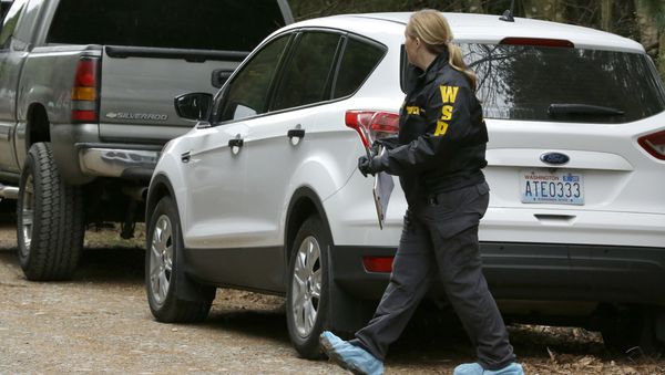 Washington State Patrol detective walks with protective foot covers on near the scene of a fatal shooting Friday, Feb. 26, 2016, near Belfair, Wash Washington State Patrol detective walks with protective foot covers on near the scene of a fatal shooting Friday, Feb. 26, 2016, near Belfair, Wash - Sputnik International