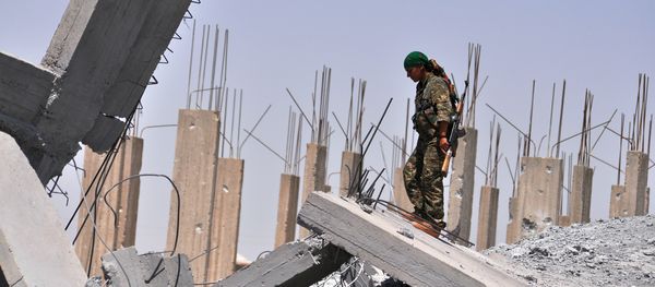 A female fighter from the Kurdish People Protection Unit (YPG) looks at destruction in the Syrian town of Ain Issi, some 50 kilometres north of Raqqa (File) - Sputnik International