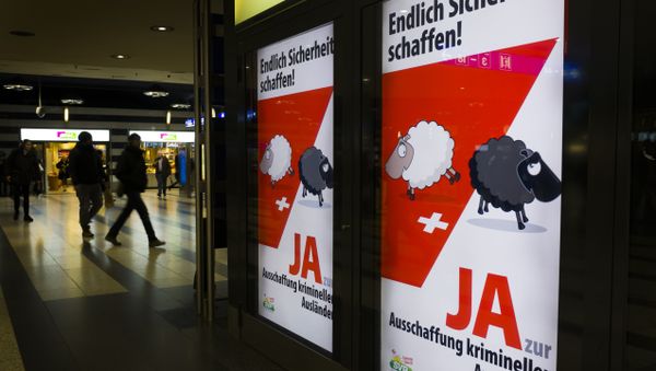 People walk past backlit posters of the right-wing populist Swiss People's Party (SVP) that translate from German as Finally Create Security to advertise their initiative for the eviction of criminal foreigners in Zurich on February 25, 2016 - Sputnik International