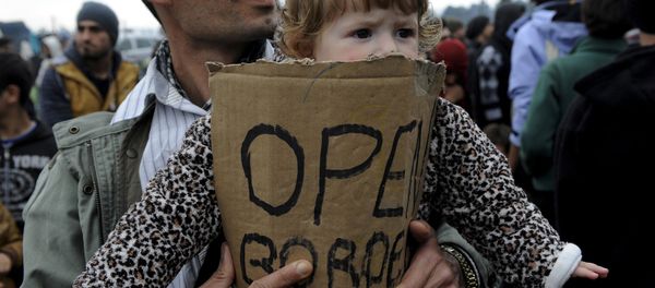 A stranded refugee holds a child during a protest at the Greek-Macedonian border as they wait for the border crossing to reopen near the Greek village of Idomeni, February 28, 2016. A stranded refugee holds a child during a protest at the Greek-Macedonian border as they wait for the border crossing to reopen near the Greek village of Idomeni, February 28, 2016. - Sputnik International
