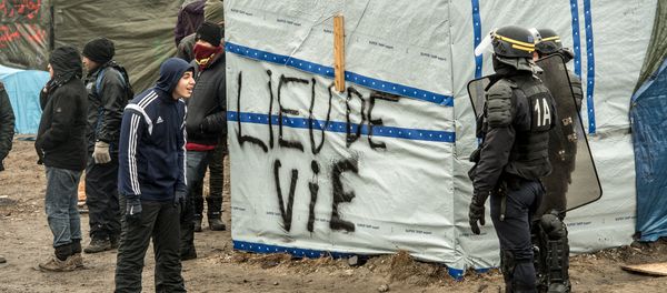 A migrant (L) talks to an anti-riot policeman during the dismantling of half of the Jungle migrant camp in the French northern port city of Calais, on March 1, 2016. - Sputnik International