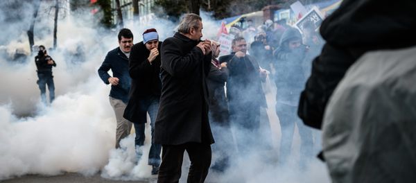 Men run and cover their faces as Turkish anti-riot police officers use tear gas to disperse supporters in front of the headquarters of the Turkish daily newspaper Zaman in Istanbul on March 5, 2016, after Turkish authorities seized the headquarters in a midnight raid Men run and cover their faces as Turkish anti-riot police officers use tear gas to disperse supporters in front of the headquarters of the Turkish daily newspaper Zaman in Istanbul on March 5, 2016, after Turkish authorities seized the headquarters in a midnight raid - Sputnik International