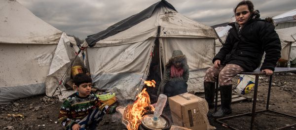 Young migrants get warm around a brazier in the migrants camp of Grande-Synthe, near Dunkirk, on January 20, 2016, where almost some 2,500 migrants and refugees live, mostly Iraqi Kurds and Syryans Young migrants get warm around a brazier in the migrants camp of Grande-Synthe, near Dunkirk, on January 20, 2016, where almost some 2,500 migrants and refugees live, mostly Iraqi Kurds and Syryans - Sputnik International
