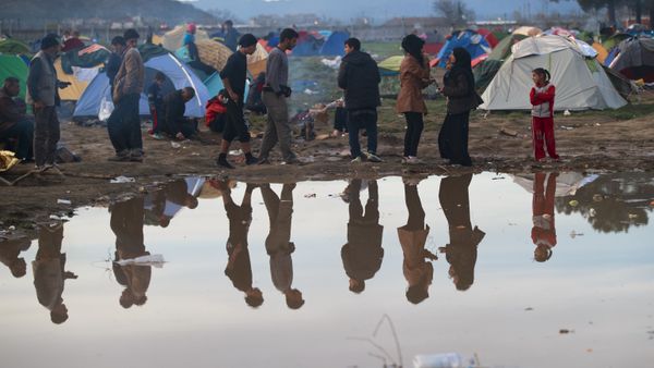 Migrants are reflected in a puddle at the northern Greek border station of Idomeni, Tuesday, March 8, 2016. - Sputnik International