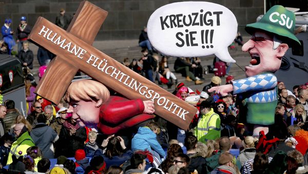 A carnival float with papier-mache caricature mocking German Chancellor Angela Merkel is displayed at a postponed Rosenmontag (Rose Monday) parade, at one location in Duesseldorf, Germany, March 13, 2016. Words read 'Crucify her' 'Humane politics for migrants' A carnival float with papier-mache caricature mocking German Chancellor Angela Merkel is displayed at a postponed Rosenmontag (Rose Monday) parade, at one location in Duesseldorf, Germany, March 13, 2016. Words read 'Crucify her' 'Humane politics for migrants' - Sputnik International