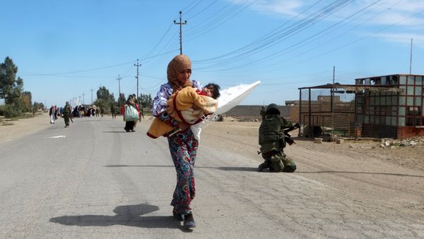 A woman carrying her child flees to safe areas with help from Iraqi security forces, west of Ramadi, March 9, 2016 - Sputnik International