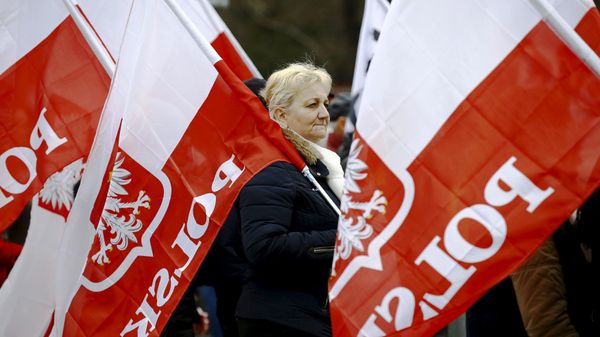 A woman holds the Polish national flag as she takes part in a march demanding their government to respect the country's constitution in Warsaw, Poland, March 12, 2016. - Sputnik International