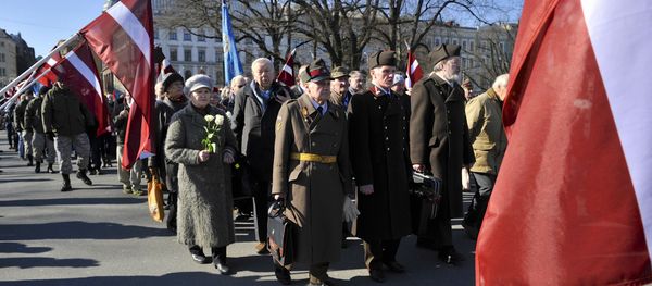 People carry flowers and Latvian flags as they march to the Freedom Monument to commemorate World War II veterans who fought in Waffen SS divisions, in Riga, Latvia, Monday, March 16, 2015 - Sputnik International