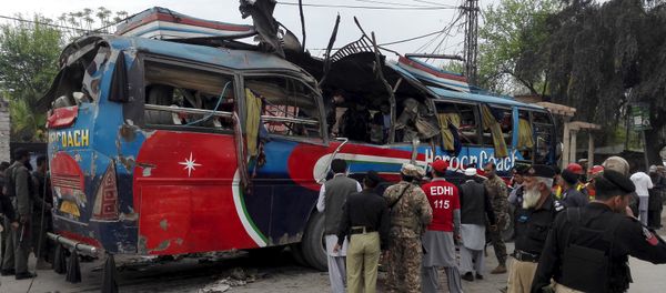 Policemen and rescue officials walk near a bus damaged in a bomb blast in Peshawar, Pakistan March 16, 2016 - Sputnik International