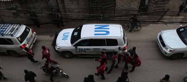 UN vehicles escorting a Red Crescent convoy carrying humanitarian aid arrive in Kafr Batna, in the rebel-held Eastern Ghouta area, on the outskirts of the capital Damascus on February 23, 2016 during an operation in cooperation with the UN to deliver aid to thousands of besieged Syrians - Sputnik International