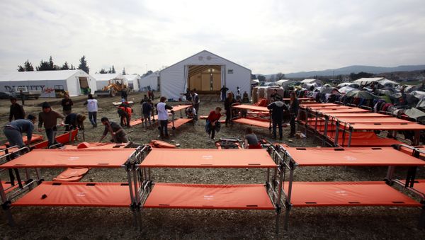 Humanitarian workers prepare new beds for the migrants in the camp at the northern Greek border post of Idomeni, Greece, Friday, March 18, 2016. - Sputnik International