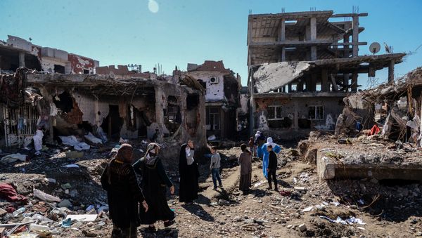 Woman walk next to ruined houses and shops on March 8, 2016 during International Women's day in Cizre district. Residents of Cizre in southeastern Turkey began returning home Wednesday after authorities partially lifted a curfew in place since December for a controversial operation against Kurdish rebels which left many homes destroyed. - Sputnik International