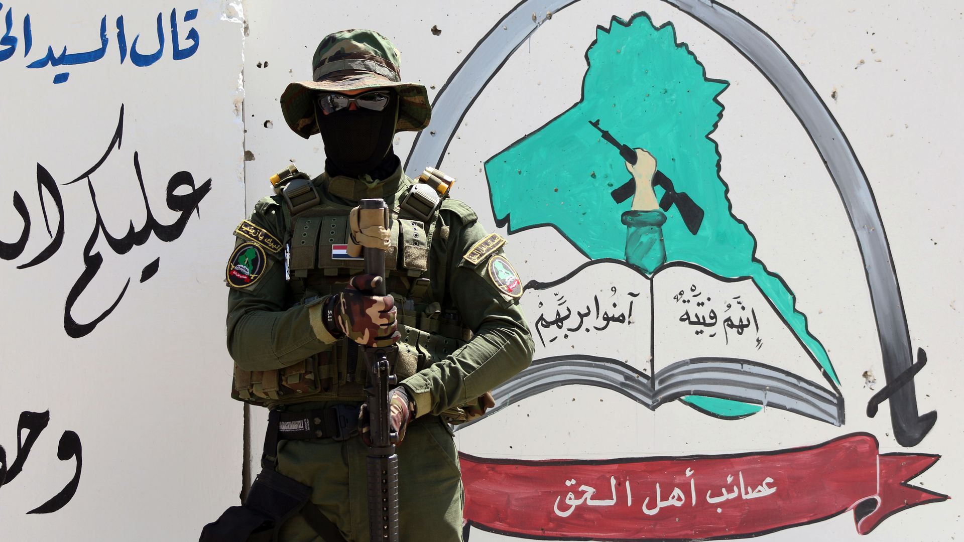 An Iraqi fighter of the Shiite group Asaib Ahl al-Haq (The League of the Righteous) stands guard outside the militia's headquarters on May 18, 2015 in the Iraqi mainly Shiite southern city of Basra An Iraqi fighter of the Shiite group Asaib Ahl al-Haq (The League of the Righteous) stands guard outside the militia's headquarters on May 18, 2015 in the Iraqi mainly Shiite southern city of Basra - Sputnik International, 1920, 07.10.2021