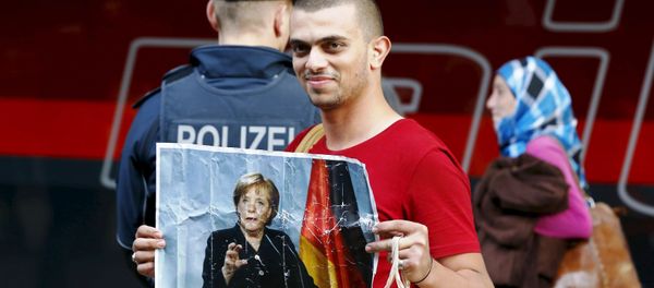 A migrant holds a picture of German Chancellor Angela Merkel after arriving to the main railway station in Munich, Germany, in this September 5, 2015. - Sputnik International