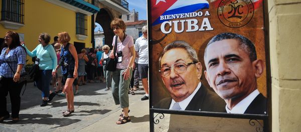 Tourists walk next to a poster of Cuban President Raul Castro and US president Barack Obama in Havana, on March 18, 2016 - Sputnik International