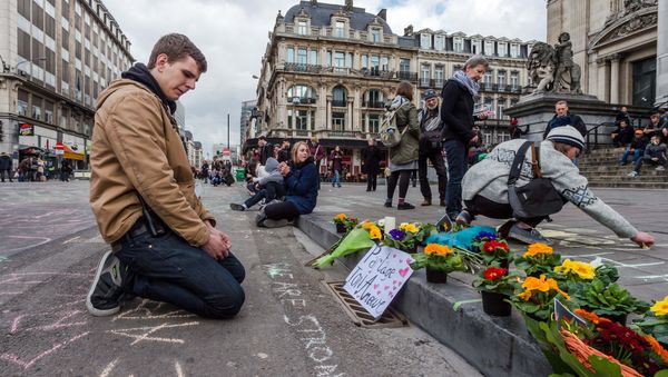A man looks at flowers and messages outside the stock exchange in Brussels on Tuesday, March 22, 2016 - Sputnik International
