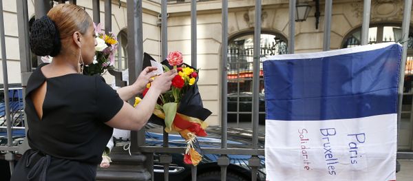 A woman leaves a bouquet of flowers in the Belgian national colours next to a French national flag with the lettering 'Paris - Brussels - Solidarity' at the fence of the Belgian embassy in Paris on March 22, 2016 A woman leaves a bouquet of flowers in the Belgian national colours next to a French national flag with the lettering 'Paris - Brussels - Solidarity' at the fence of the Belgian embassy in Paris on March 22, 2016 - Sputnik International