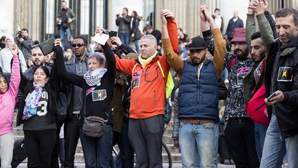 People stand hand in hand in tribute to victims at a makeshift memorial in front of the stock exchange at the Place de la Bourse (Beursplein) in Brussels on March 22, 2016 - Sputnik International