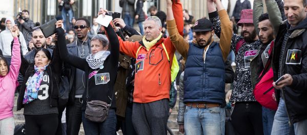 People stand hand in hand in tribute to victims at a makeshift memorial in front of the stock exchange at the Place de la Bourse (Beursplein) in Brussels on March 22, 2016 - Sputnik International