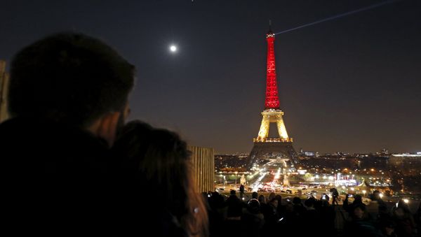 A couple looks at the Eiffel Tower lit up in the colours of the Belgian flag in tribute to the victims of today's bomb attacks in Brussels, in Paris, France, March 22, 2016 - Sputnik International