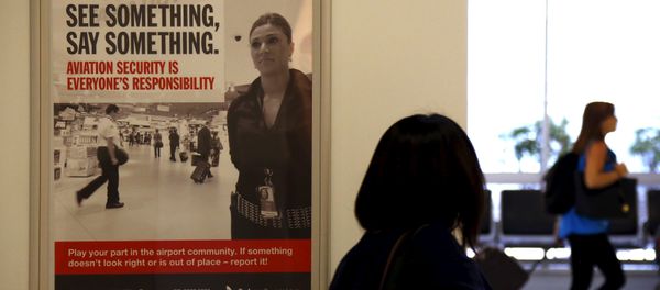 A poster regarding airport security hangs from a wall as passengers walk around the departures area at Sydney International Airport, Australia, March 23, 2016. - Sputnik International