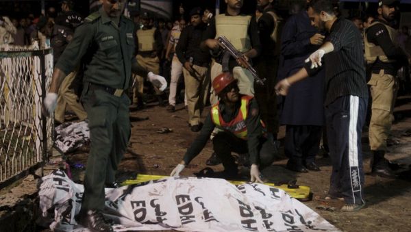 Rescue workers move a body from the site of a blast outside a public park in Lahore, Pakistan - Sputnik International