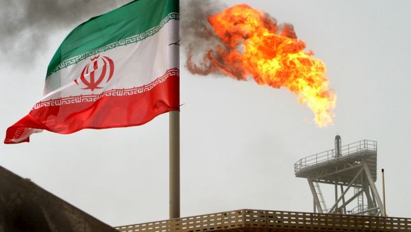 A gas flare on an oil production platform in the Soroush oil fields is seen alongside an Iranian flag in the Persian Gulf, in this July 25, 2005 file photo - Sputnik International