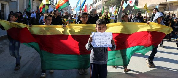 Kurdish children hold a flag of the Kurdish People's Protection Units (YPG) political wing, the Democratic Union Party (PYD), and banners during a demonstration against the exclusion of Syrian-Kurds from the Geneva talks in the northeastern Syrian city of Qamishli on February 4, 2016 Kurdish children hold a flag of the Kurdish People's Protection Units (YPG) political wing, the Democratic Union Party (PYD), and banners during a demonstration against the exclusion of Syrian-Kurds from the Geneva talks in the northeastern Syrian city of Qamishli on February 4, 2016 - Sputnik International