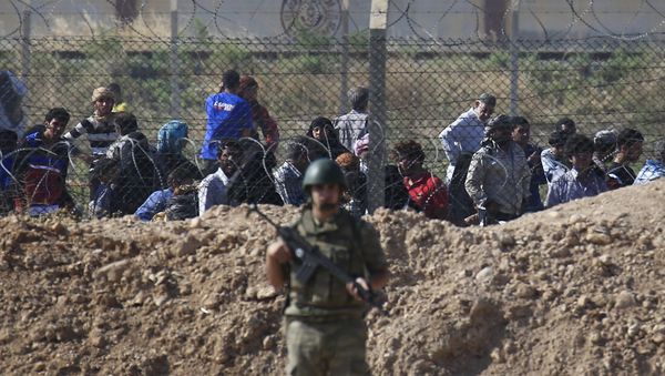 File photo of a Turkish army soldier guards the border area with Syria as in the background Syrian refugees wait in Syria in order to cross into Turkey, in Akcakale, southeastern Turkey, Monday, June 15, 2015 - Sputnik International