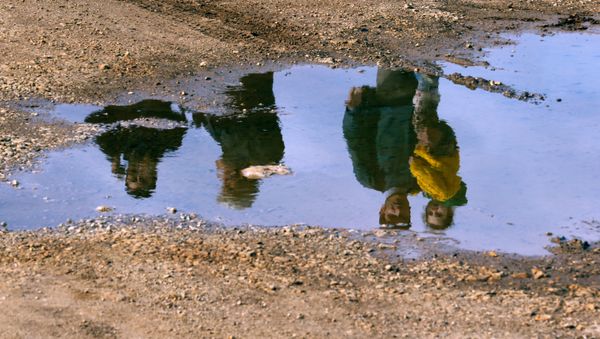 Syrian refugees are reflected in a puddle as they wait on a roadside after Turkish police prevented them from sailing off to the Greek island of Farmakonisi by dinghies, near a beach in the western Turkish coastal town of Didim, Turkey March 9, 2016. Syrian refugees are reflected in a puddle as they wait on a roadside after Turkish police prevented them from sailing off to the Greek island of Farmakonisi by dinghies, near a beach in the western Turkish coastal town of Didim, Turkey March 9, 2016. - Sputnik International