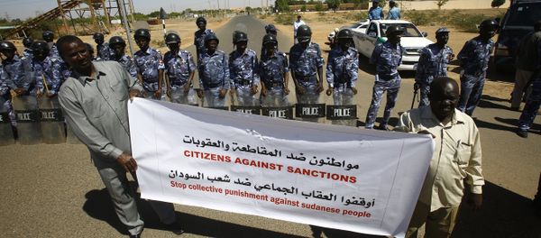 Sudanese police stand guard as two men hold a banner outside the US embassy in the capital Khartoum on November 3, 2015, to protest against sanctions imposed on their country by the United States - Sputnik International