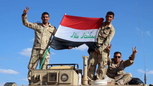Iraqi government forces wave the national flag from their vehicles in the village of Mohammadi, a few miles north of Heet, in Iraq's western province of Anbar on March 18, 2016. - Sputnik International