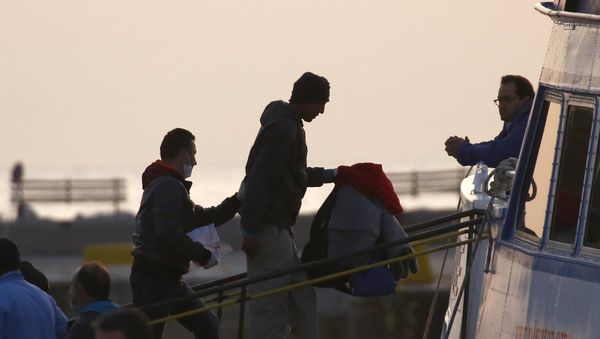 A Frontex officer (L) escorts a migrant as he boards on a Turkish-flagged passenger boat to be returned to Turkey, on the Greek island of Lesbos, April 4, 2016. - Sputnik International