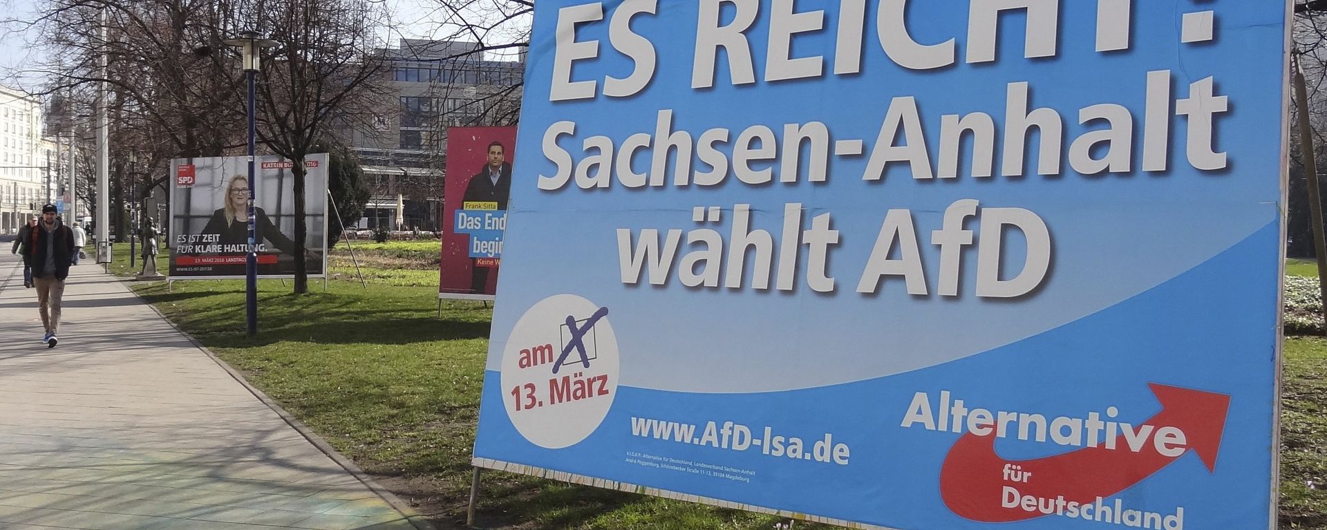 A man walks past a campaign poster of right-populist AfD party reading It's enough - Saxony-Anhalt elects AfD in Magdeburg, Germany. - Sputnik International, 1920, 06.09.2026