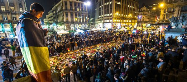 A man wrapped in a Belgian flag holds a candle as people gather at a makeshift memorial in front of Brussel's Stock Exchange on Place de la Bourse (Beursplein) on March 24, 2016 - Sputnik International