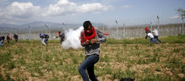 A migrant flees from teargas smoke thrown by Macedonian police on a crowd of more than 500 refugees and migrants protesting next to a border fence at a makeshift camp at the Greek-Macedonian border near the village of Idomeni, Greece A migrant flees from teargas smoke thrown by Macedonian police on a crowd of more than 500 refugees and migrants protesting next to a border fence at a makeshift camp at the Greek-Macedonian border near the village of Idomeni, Greece - Sputnik International