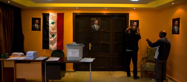 An empty ballot box with Arabic that reads, Syrian Arab Republic, Damascus Governorate, Election ballot box, number 210, is seen at a polling station as workers hang portraits of Syrian President Bashar Assad in Damascus, Syria, Tuesday, April 12, 2016. An empty ballot box with Arabic that reads, Syrian Arab Republic, Damascus Governorate, Election ballot box, number 210, is seen at a polling station as workers hang portraits of Syrian President Bashar Assad in Damascus, Syria, Tuesday, April 12, 2016. - Sputnik International