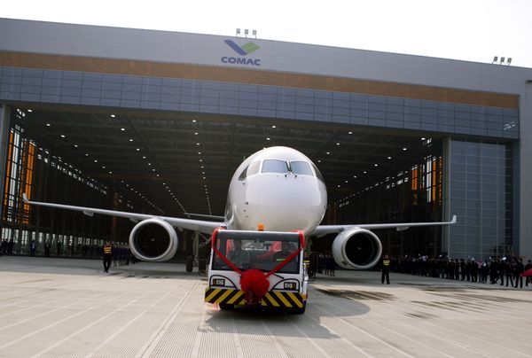 Chinese workers wave flags as a truck pulls out the first twin-engine 158-seater C919 passenger plane made by The Commercial Aircraft Corp. of China (COMAC) during a ceremony at the company's hangar near the Pudong International Airport in Shanghai, China. (File) - Sputnik International