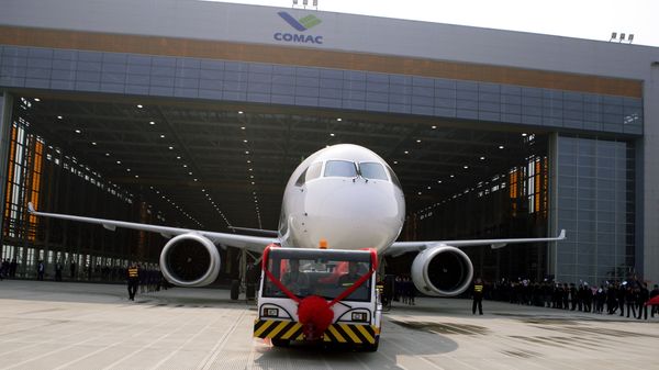 Chinese workers wave flags as a truck pulls out the first twin-engine 158-seater C919 passenger plane made by The Commercial Aircraft Corp. of China (COMAC) during a ceremony at the company's hangar near the Pudong International Airport in Shanghai, China. (File) Chinese workers wave flags as a truck pulls out the first twin-engine 158-seater C919 passenger plane made by The Commercial Aircraft Corp. of China (COMAC) during a ceremony at the company's hangar near the Pudong International Airport in Shanghai, China. (File) - Sputnik International