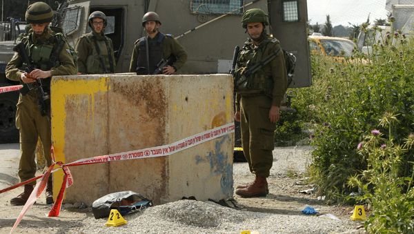 An axe is seen on the ground as Israeli soldiers stand guard at the site where a Palestinian man, armed with an axe, reportedly attacked an Israeli soldier at the entrance of al-Arroub Palestinian refugee camp, between Hebron and Bethlehem on April 14, 2016 - Sputnik International