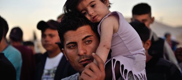 A man carries a child on his shoulders at the migrant and refugee makeshift camp near the village of Idomeni on the Greek-Macedonian border on April 16, 2016. A man carries a child on his shoulders at the migrant and refugee makeshift camp near the village of Idomeni on the Greek-Macedonian border on April 16, 2016. - Sputnik International