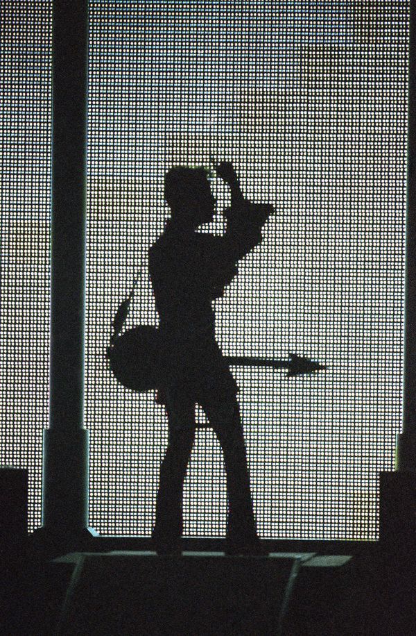 The artist formerly known as Prince, silhouetted with his guitar in front of a large television screen. - Sputnik International